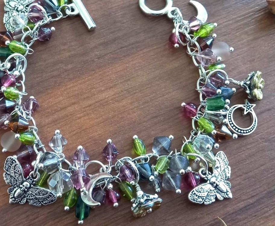 An example silver charm bracelet with glass beads and moths and moon charms
