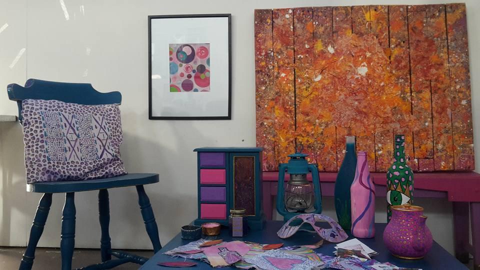 Installation artwork by Heidi Swift featuring dark sand, charity shop vintage found items, textile work, Large abstract burnt orange crate painting with texture, abstract bubble painting. Map and leopard print bottles, Mask from performance piece, handmade pots, pocket portfolio, ex mining coal lantern. old School bench. leopard print tea pot.