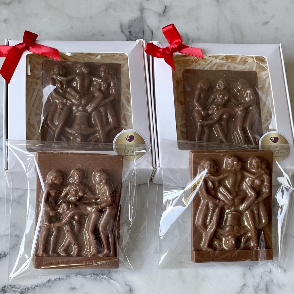 The Kamasutra chocolate bars are compact, smooth-finished bars made from glossy Belgian chocolate, moulded with raised Kamasutra-inspired silhouette designs. 
Each bar has a clean rectangular shape with softly defined edges and a satisfying thickness. The raised design catches the light and is lightly finished with edible gold lustre, highlighting the figures 