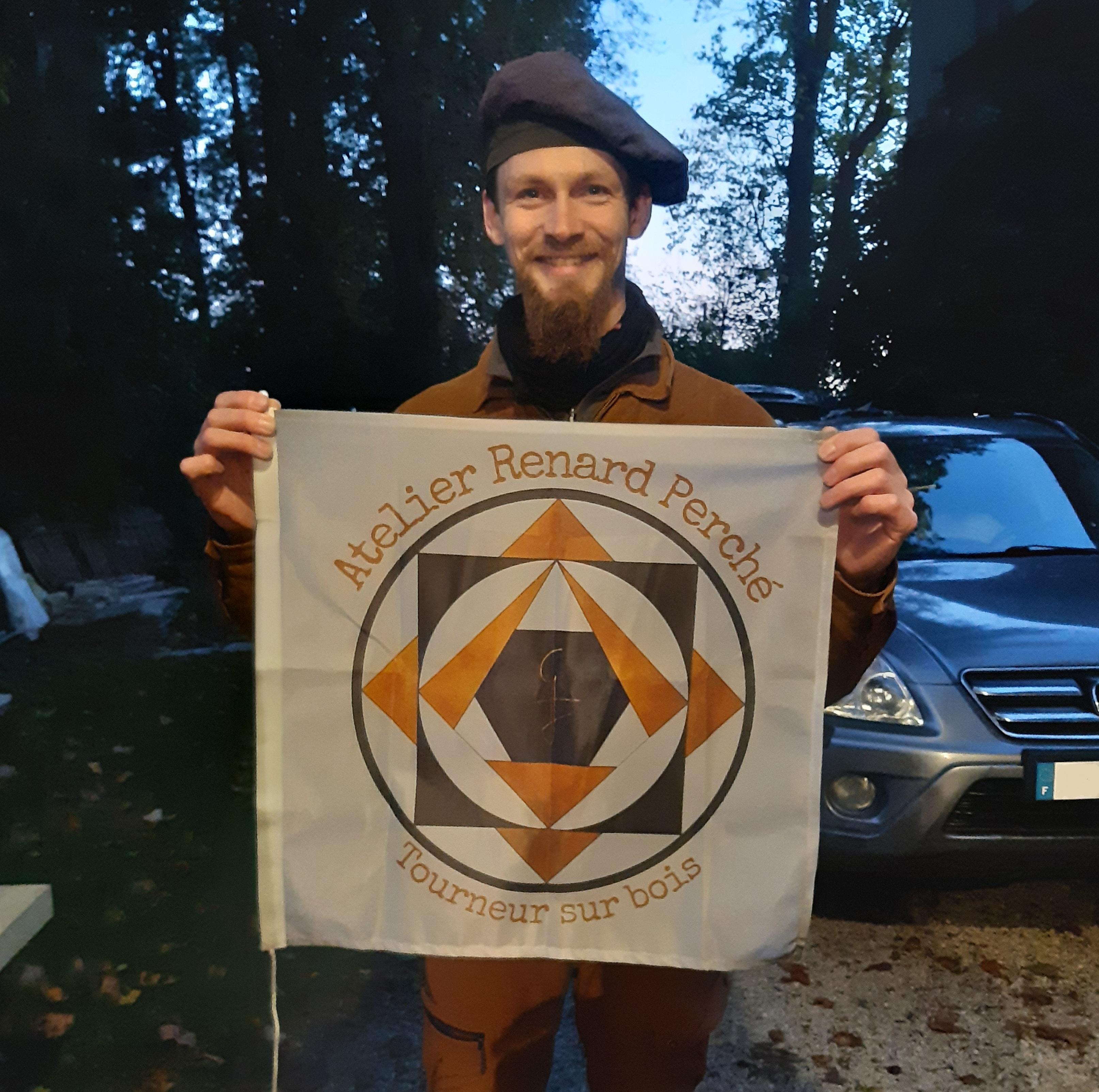 Genséric avec le drapeau de son logo atelier renard perché.