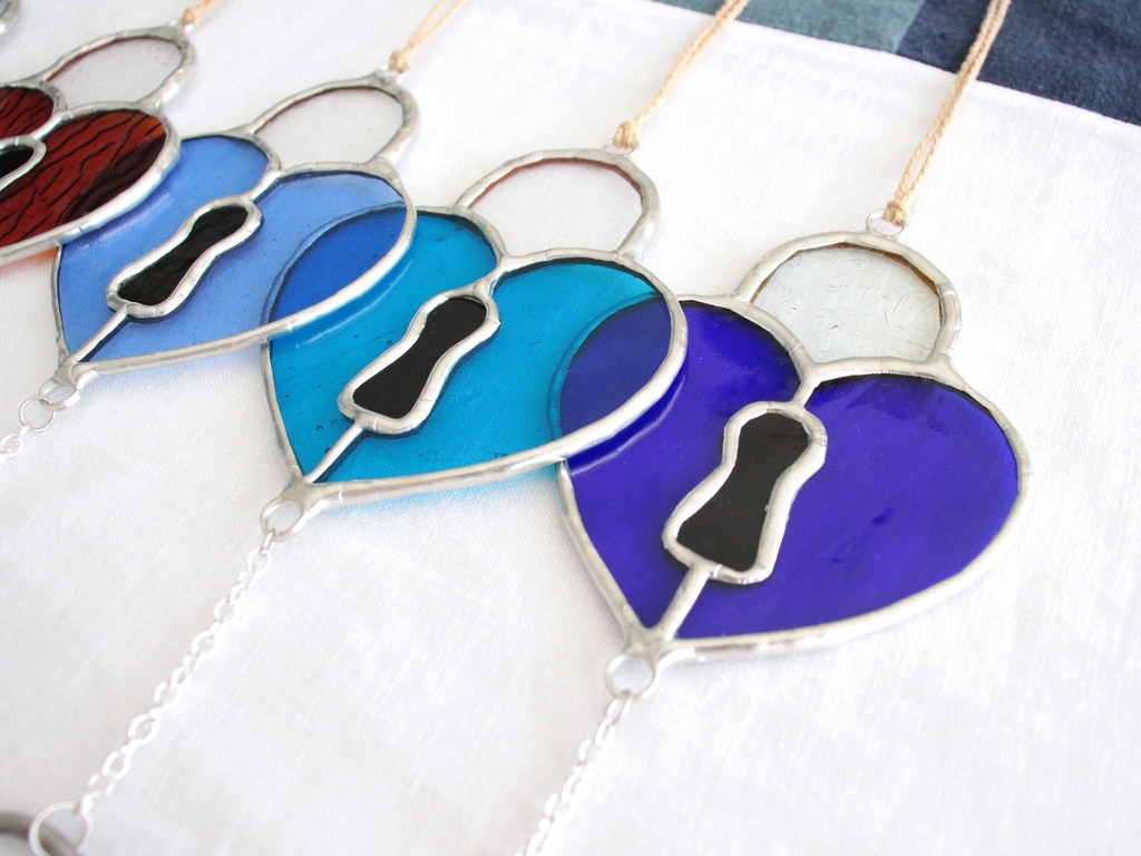 Photo de Atelier Vitraï montrant des cadenas bleus en vitrail en forme de cœur.