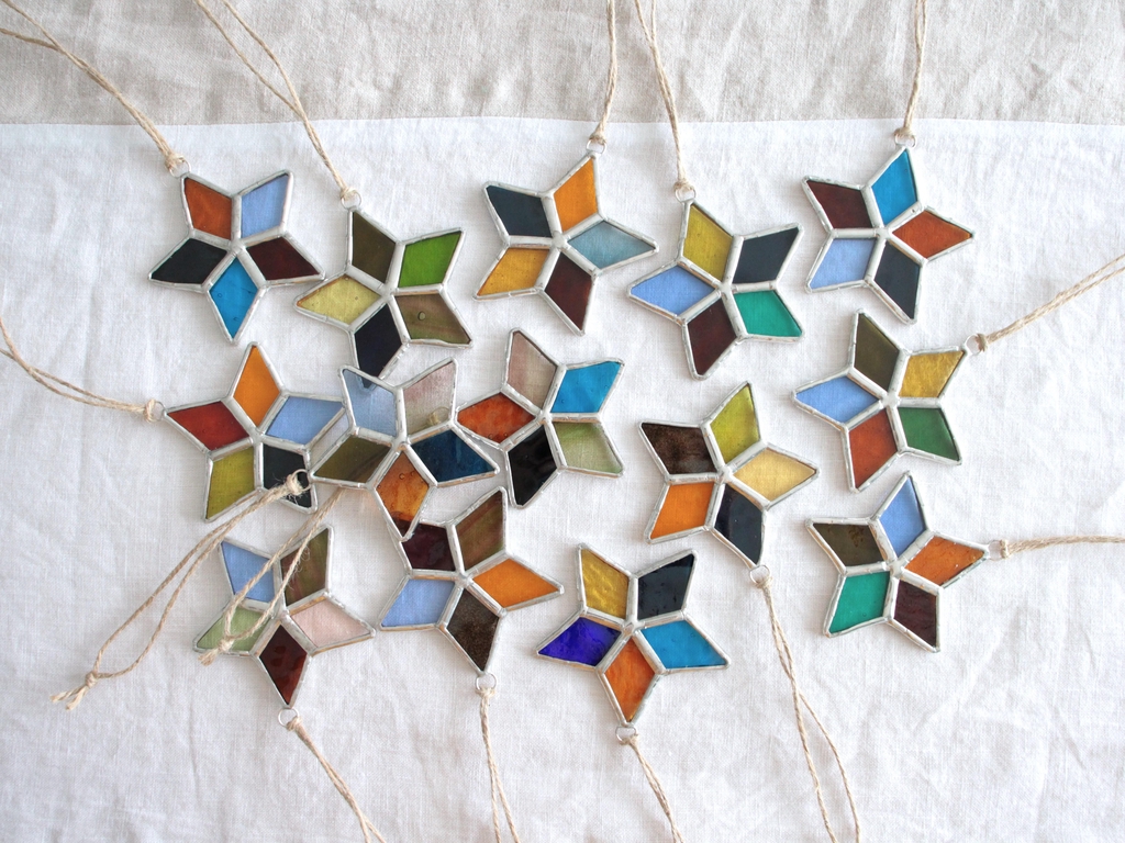 Photo de Atelier Vitraï montrant plusieurs petites étoiles multicolores en vitrail Tiffany.