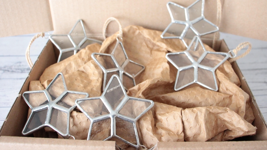 Photo de Atelier Vitraï montrant six étoiles transparentes en vitrail Tiffany, regroupées dans un coffret en carton.