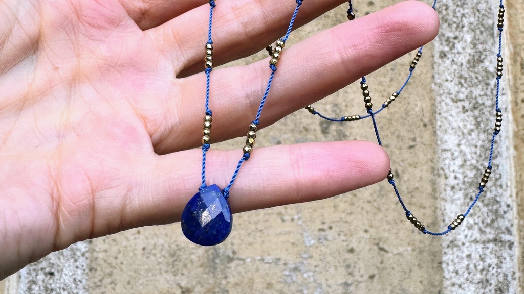 Un collier avec un pendentif lapis-lzuli et des perles en hématite dorée.