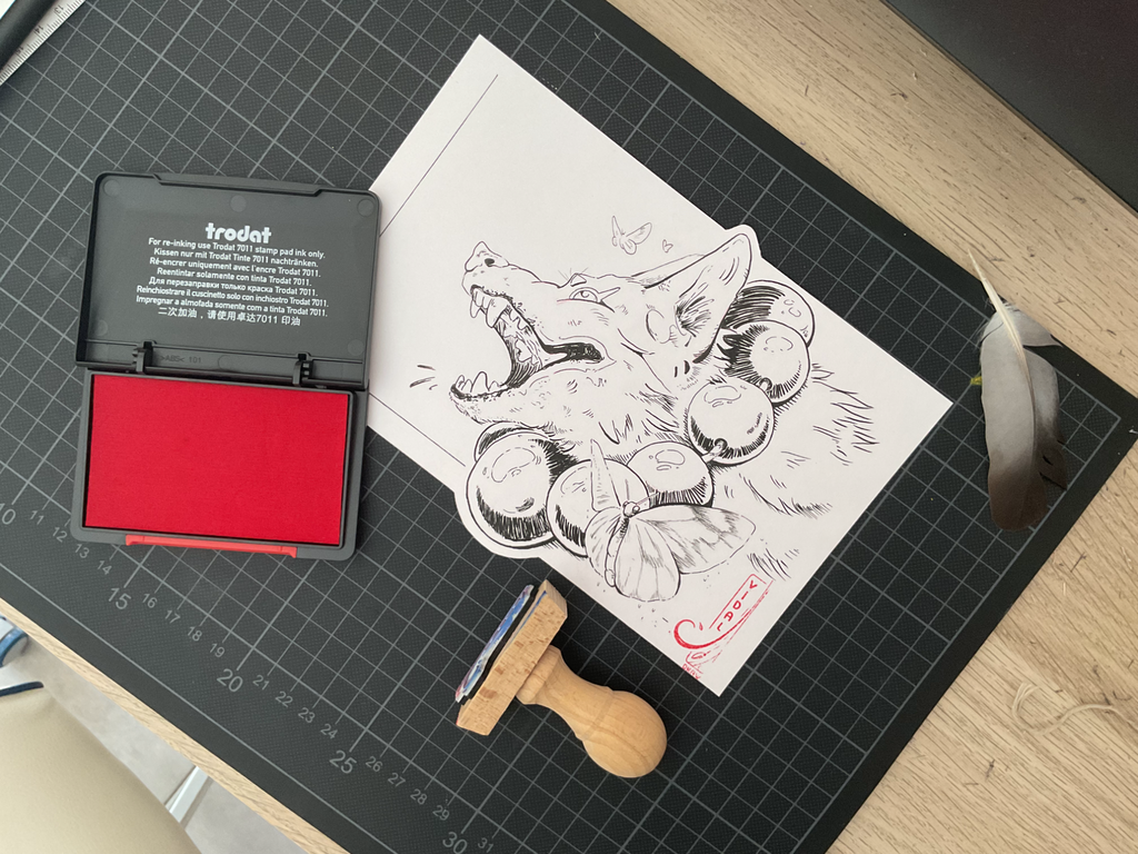 Dibujo a tinta de un lobo con polillas reboloteando alrededor, la escena está acompañada por un tintero rojo, una pluma y un sello de madera. 