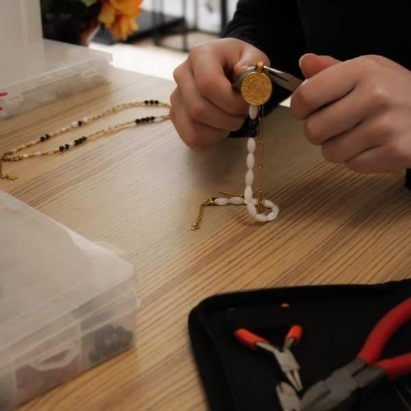 Fondatrice des Althëis qui assemble un collier en nacre et grenat.