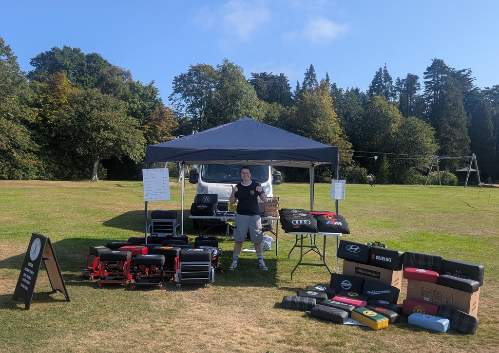 The Stool Yard founder at a car show, in the sun, surrounded by custom mechanics creepers and car accessories