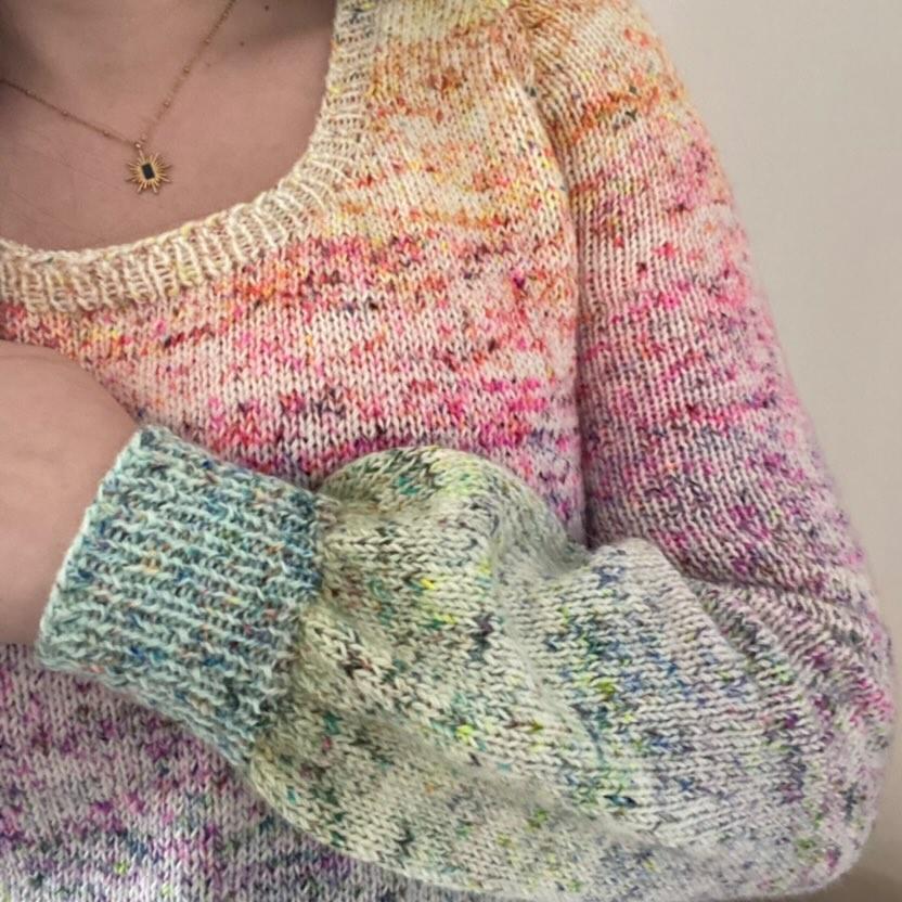 Une personne porte un pull multicolore tricoté main avec de la laine teinte à la main par Madame Guillotine