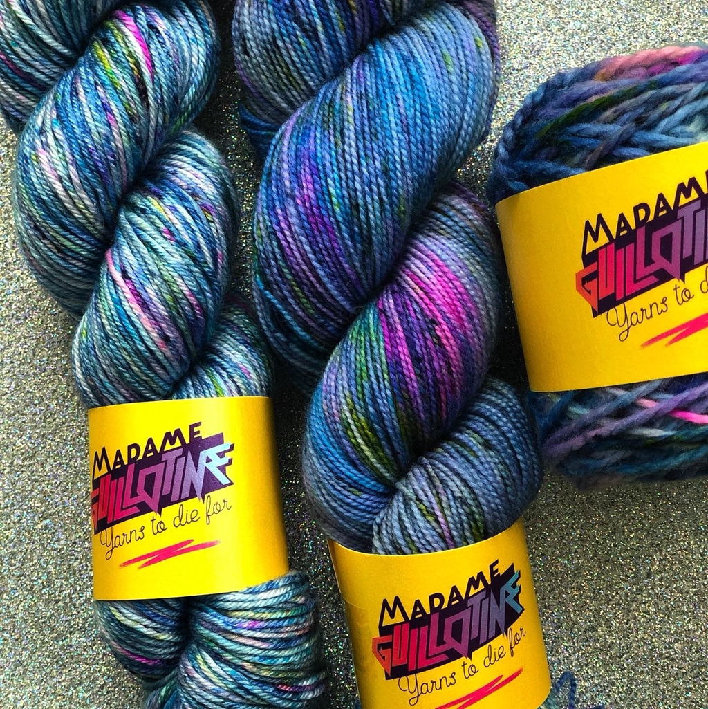 Trois écheveaux de laine teinte à la main par Madame Guillotine dans les tons bleu avec speckles rose jaune et noir