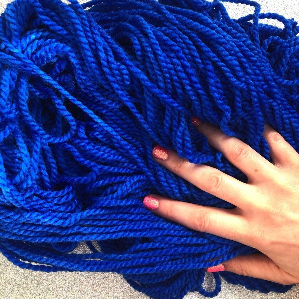 Un écheveau de laine étalé sur une table avec la main de Madame Guillotine par dessus