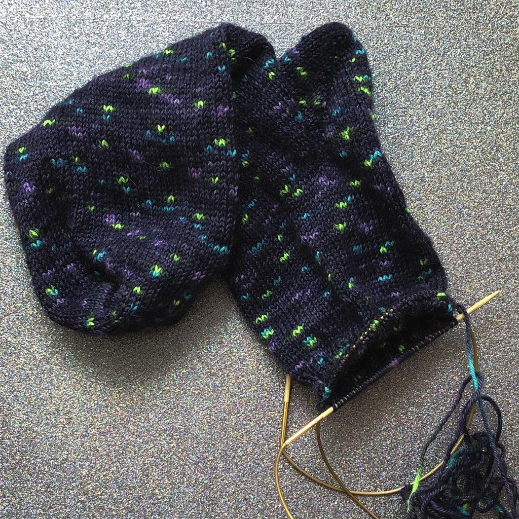 Une paire de chaussettes en train d'être tricotée dans une laine teinte à la main par Madame Guillotine