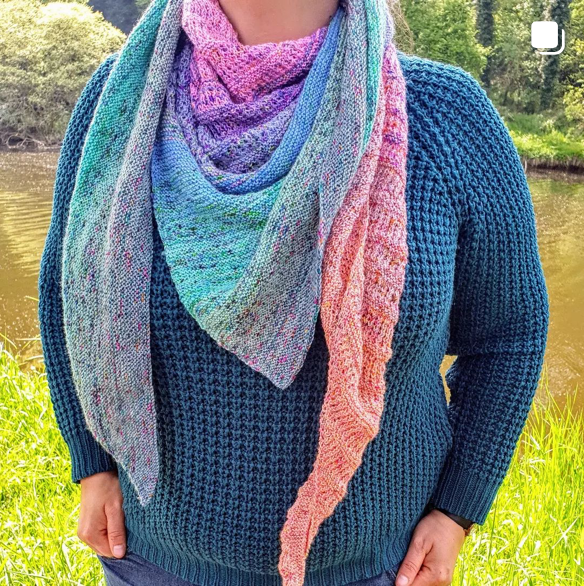 Une personne se tient face caméra, son visage est coupé. Elle porte un châle tricoté main avec de la laine teinte à la main par Madame Guillotine.