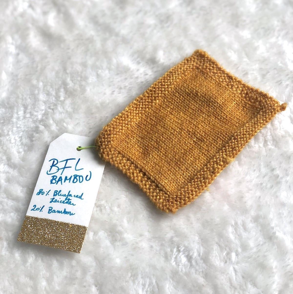 un échantillon de laine tricotée avec la base BFL Bambou teinte à la main par Madame Guillotine dans des tons caramel clair