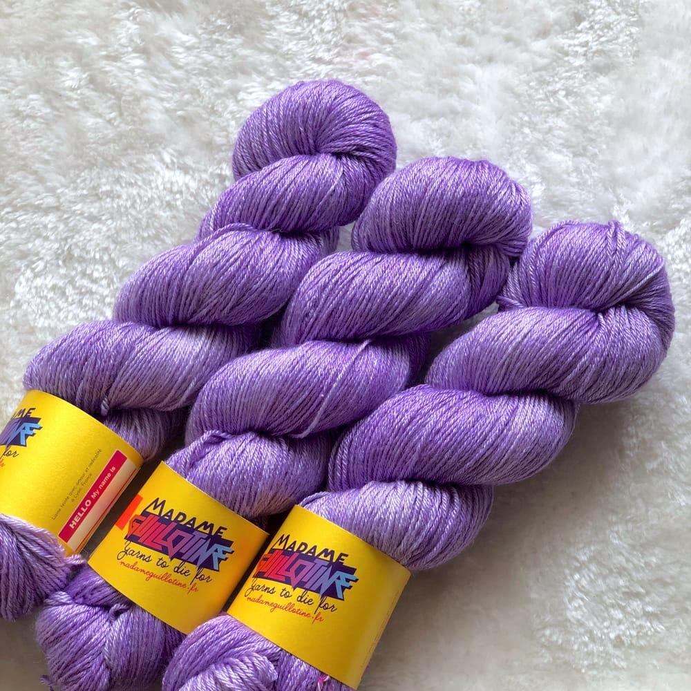 Trois écheveaux de laine lavande teinte à la main par Madame Guillotine sur un fond de fausse fourrure blanche