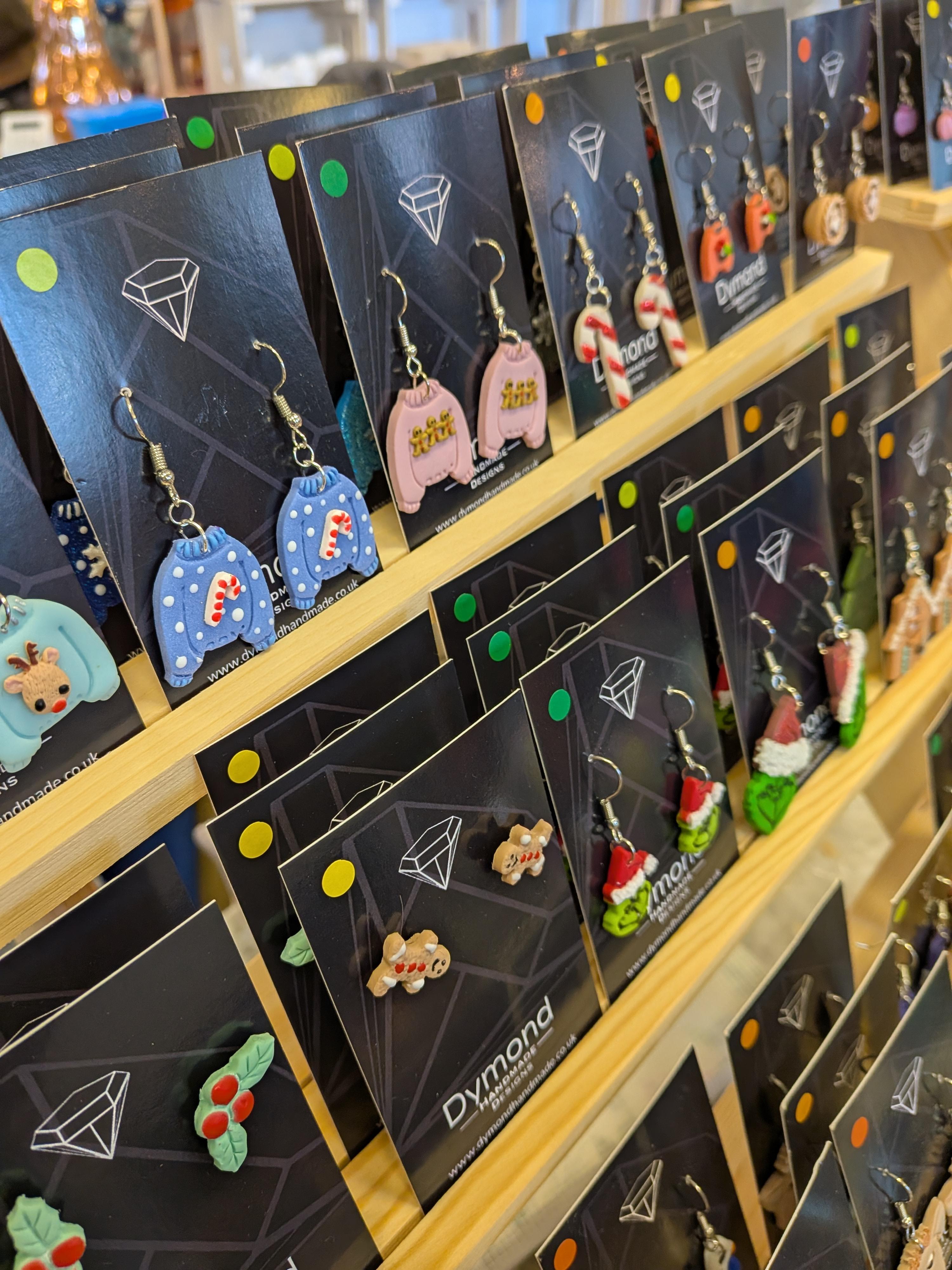 An image of handmade polymer clay earrings that are a collection of christmas themed, handcrafted earrings. Christmas jumpers, gingerbread men, and mince pie earrings