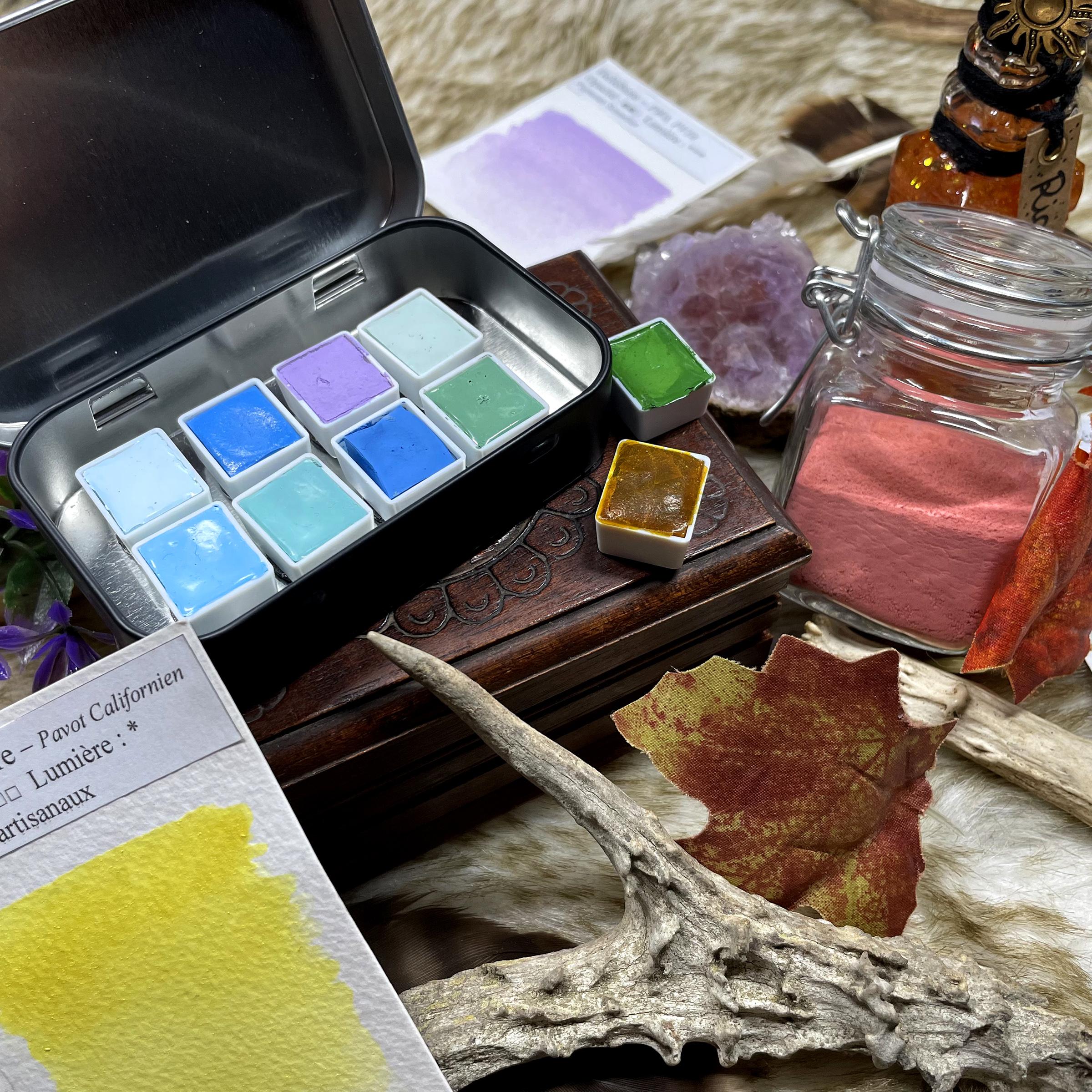 Demi-godet d'aquarelle et pot de pigment déposé en vrac sur une fausse fourrure.