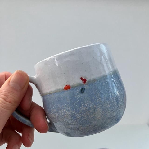 A photograph of a blue and white mug sitting by the shore