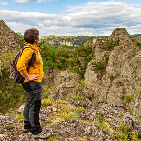Une géocacheuse en randonnée de géocaching devant un magnifique paysage