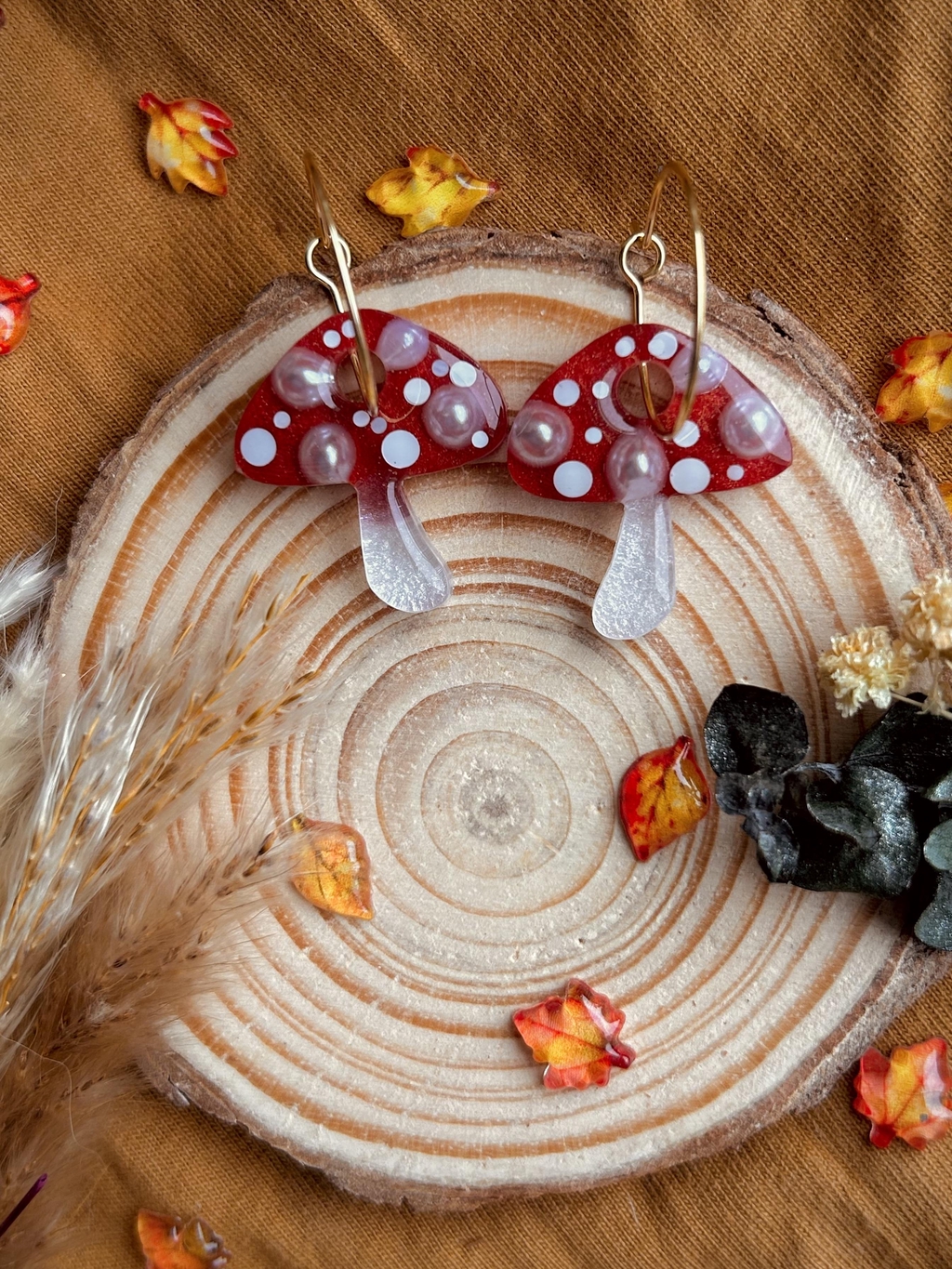 Photo is of a pair of resin, fly agaric mushrooms on gold hoops. 