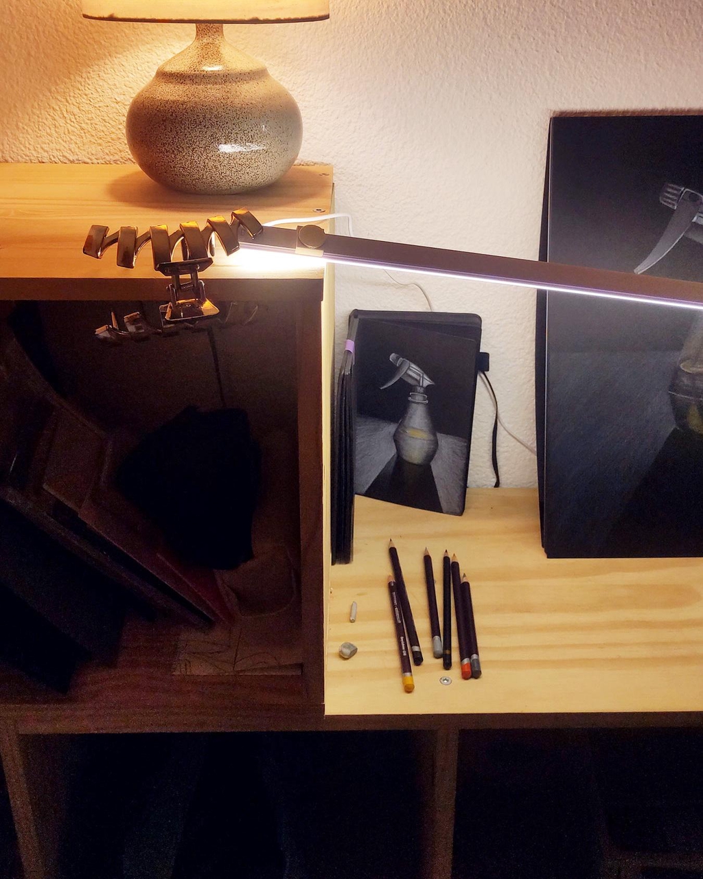 Photo d'étape de travail d'une illustration de vaporisateur. Une page du carnet de croquis et le dessin final à côté. Les illustrations sont au crayon blanc sur un papier noir.