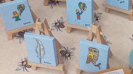Close up image of tiny paintings on tiny easels. One is a feather one is an Owl. The rest aren't visible enough to make out