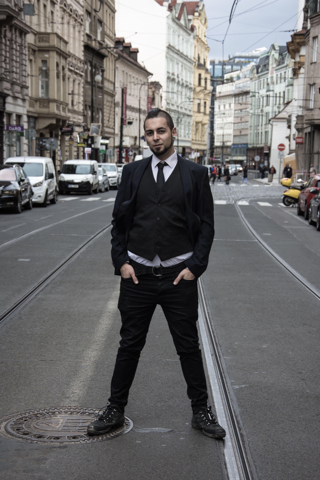 Ryan Prazer standing in the middle of a road with tram lines in the background
He wears a suit and has his hair down for this rare occasion