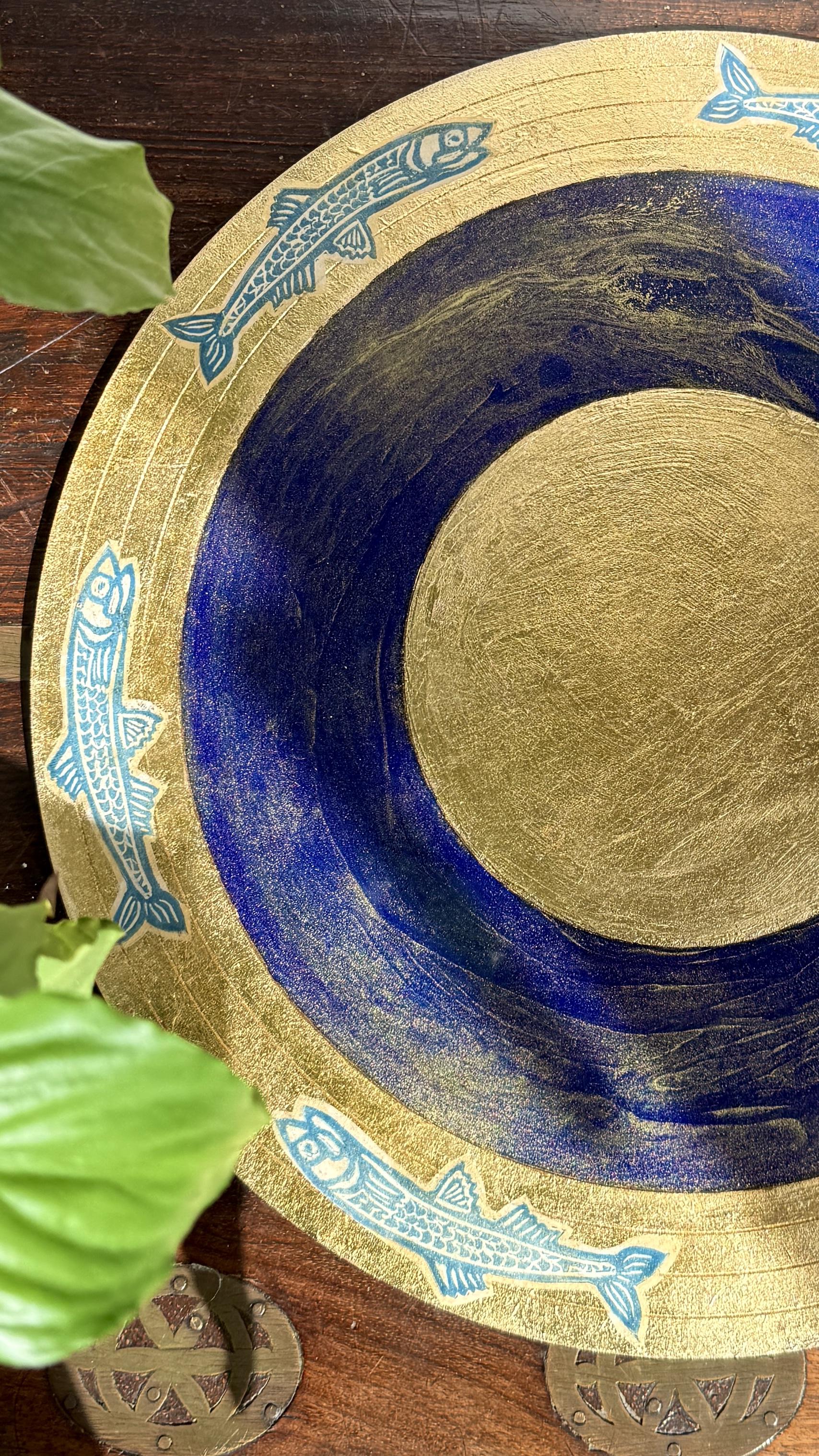 Sottopiatto artigianale legno, decorato con foglia oro, pigmento oro, linoleografie, acrilici e resina.
