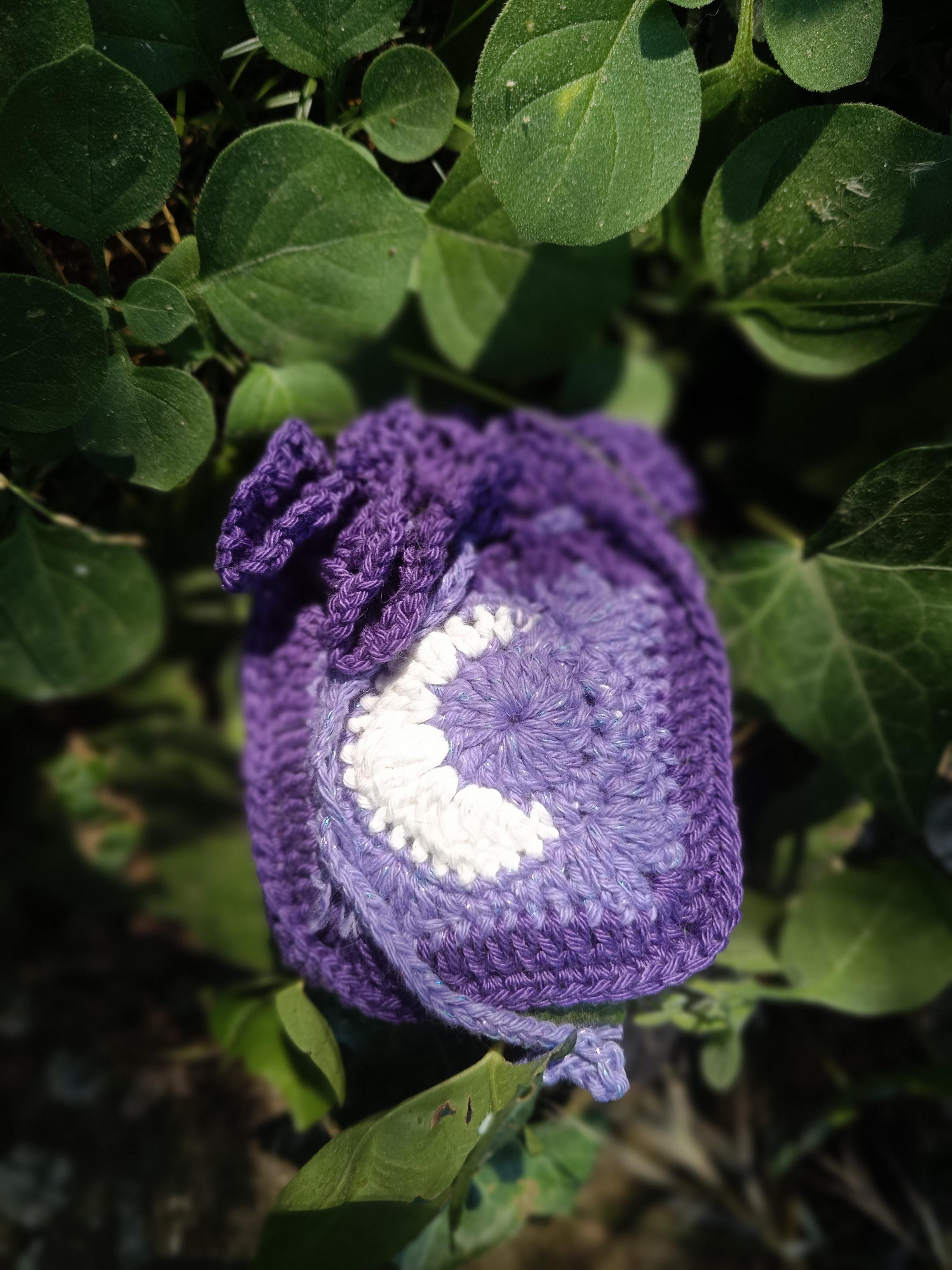 Photo d'un pochon en crochet violet avec une lune blanche en croissant.