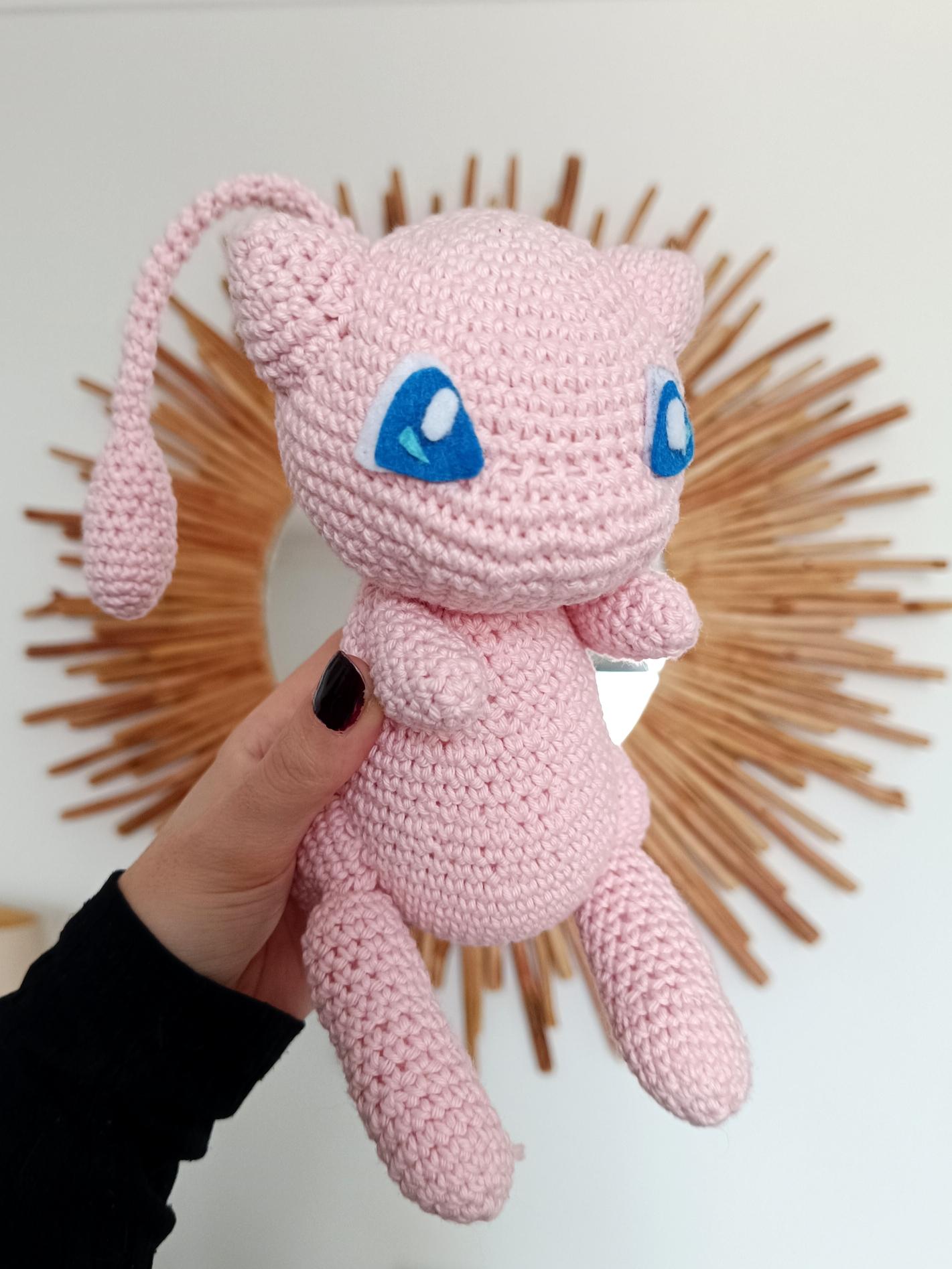 Photo de Mew en crochet, tenu dans une main.