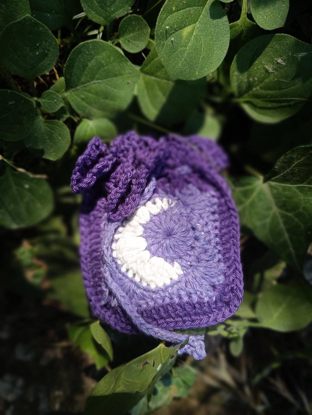 Photo d'un pochon en crochet violet avec une lune blanche en croissant.