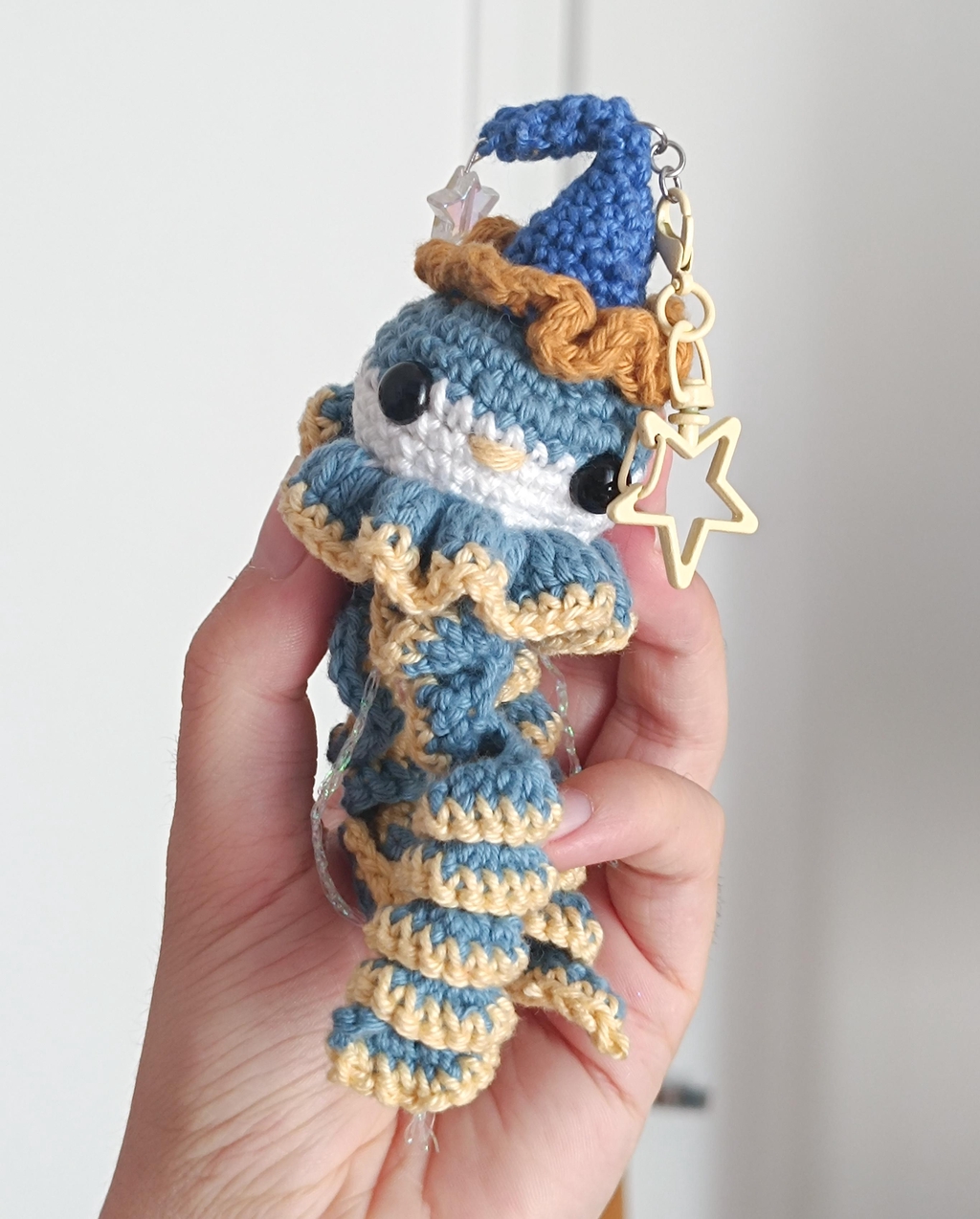 Une méduse clown, bleue et jaune, avec la tête un peu blanche, en porte clé en crochet.