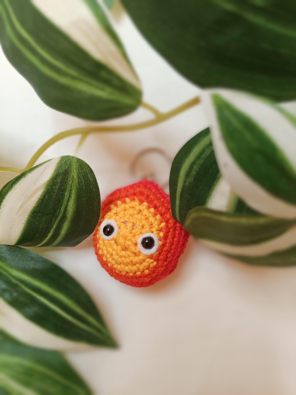 Porte-clés d'un Calcifer (le château ambulant de studio Ghibli) en crochet avec des plantes autour.