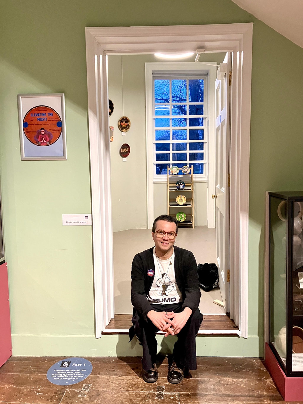 House of Frisson's artist Luciano Rocha sitting at the entrance of his solo exhibition at Bruce Castle Museum's Marker's Studio. Elevating the Misfit exhibition.