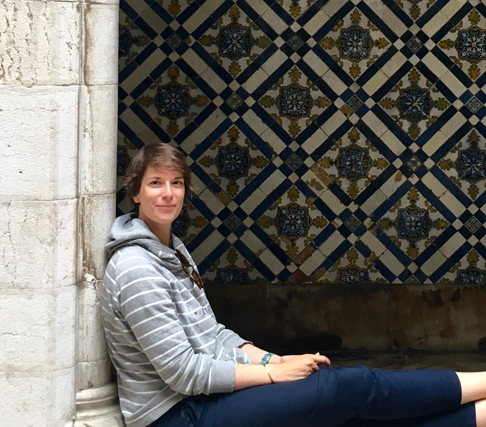 Photo présentant l'artiste Sandra Laurin, assise dans un cloître orné d'azulejos.