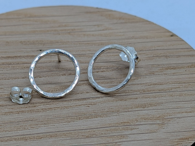 Large statement sterling silver earrings, such as hammered open drops and compass stars, designed to be weighty, high-quality, and eye-catching.