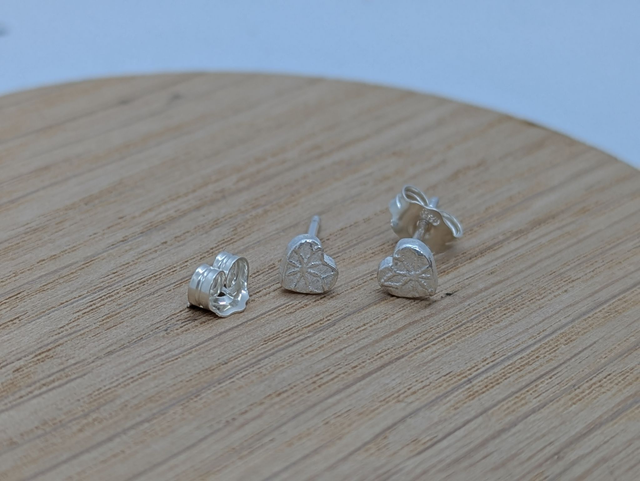 A selection of teeny tiny handmade silver stud earrings, including delicate stars and half-hoops, perfect for a subtle, everyday glow or multiple piercings.