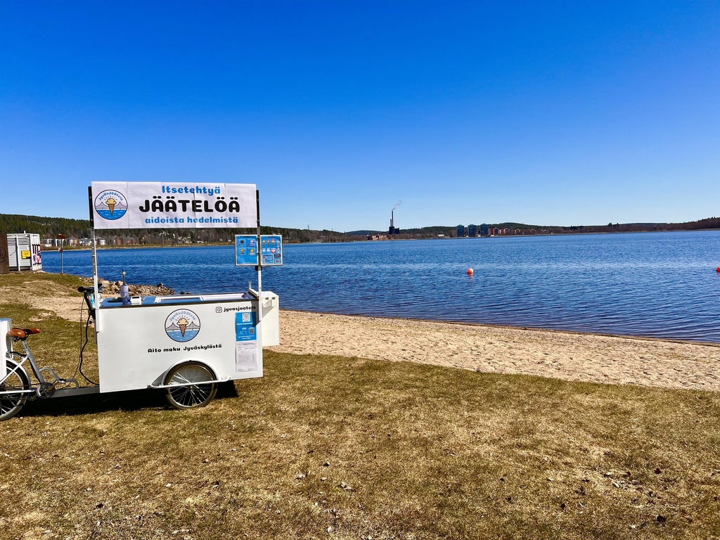 Taustakuva, jossa näkyy JyväsJäätelön jäätelöpyörä sisätiloissa.