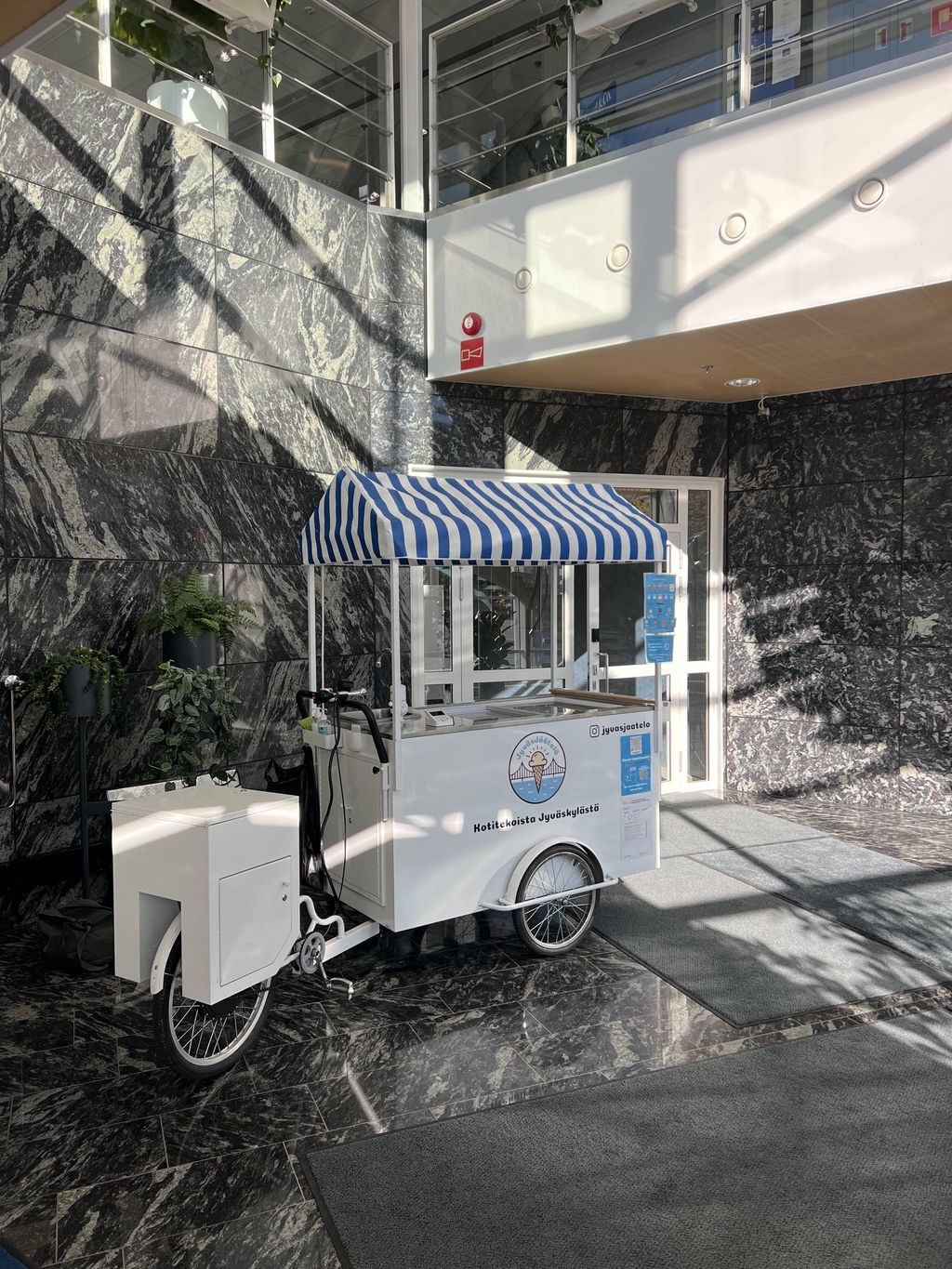 Taustakuva, jossa näkyy JyväsJäätelön jäätelöpyörä sisätiloissa.