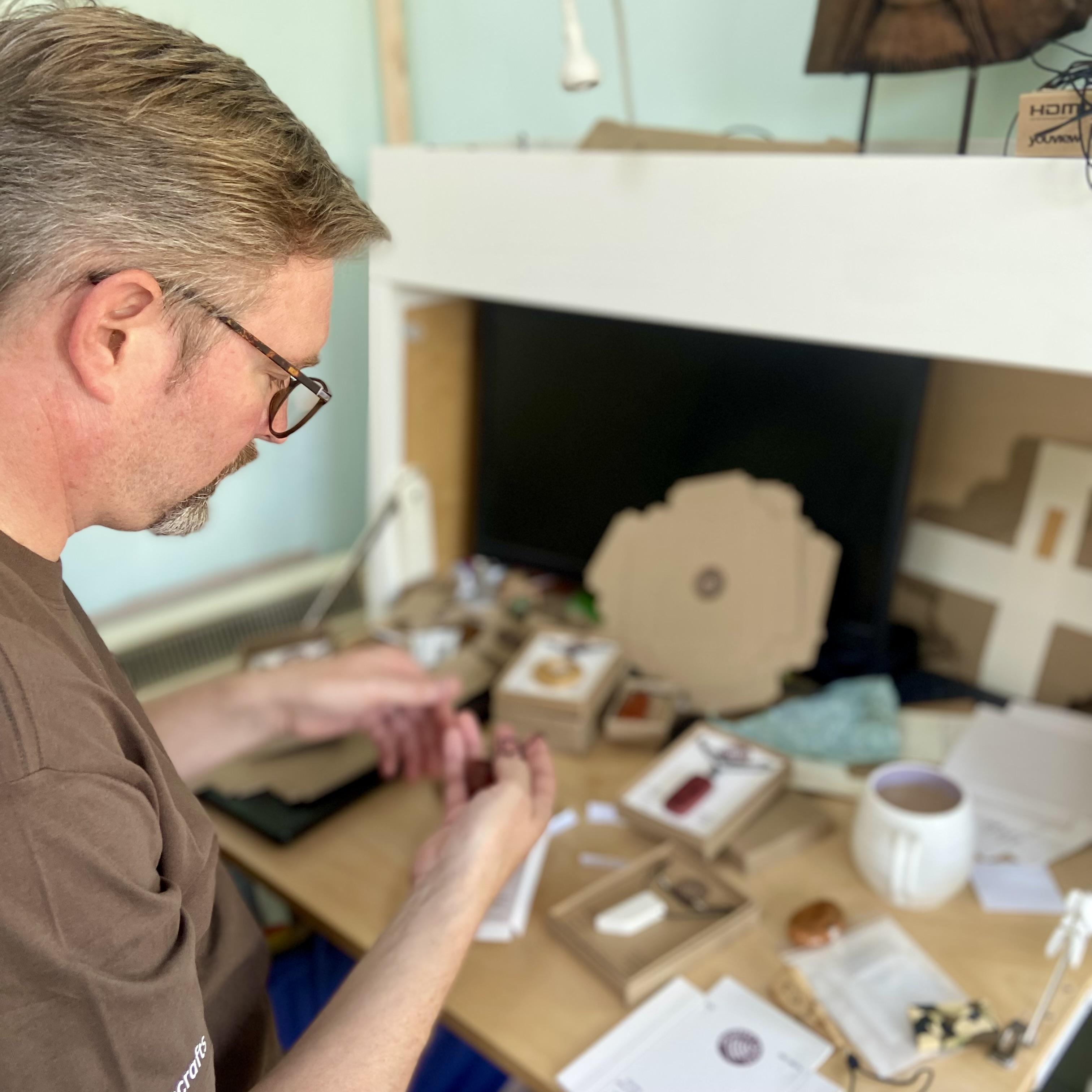 Colin at a work desk with jewellery in boxes