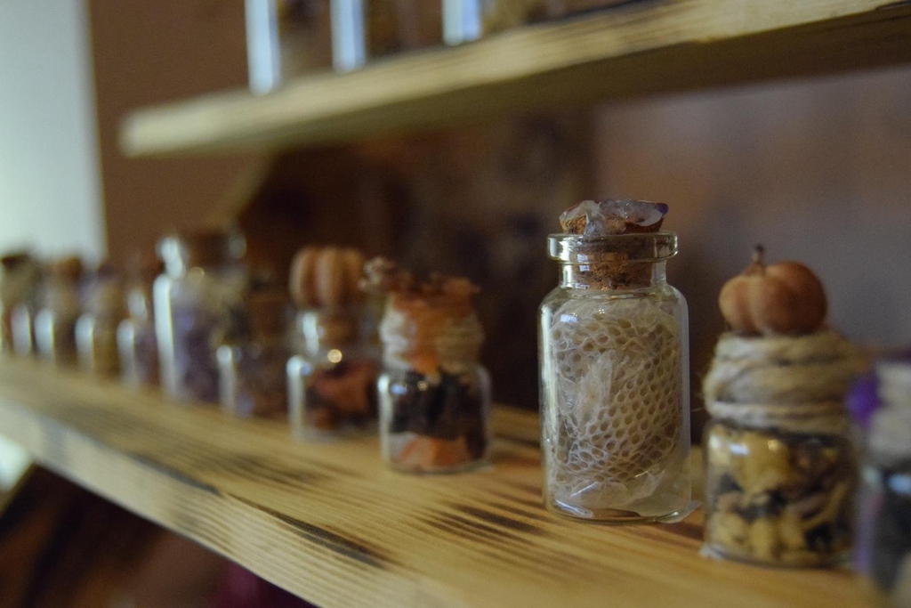 A photograph of small spell jars filled with snakeskin, crystals and herbs.