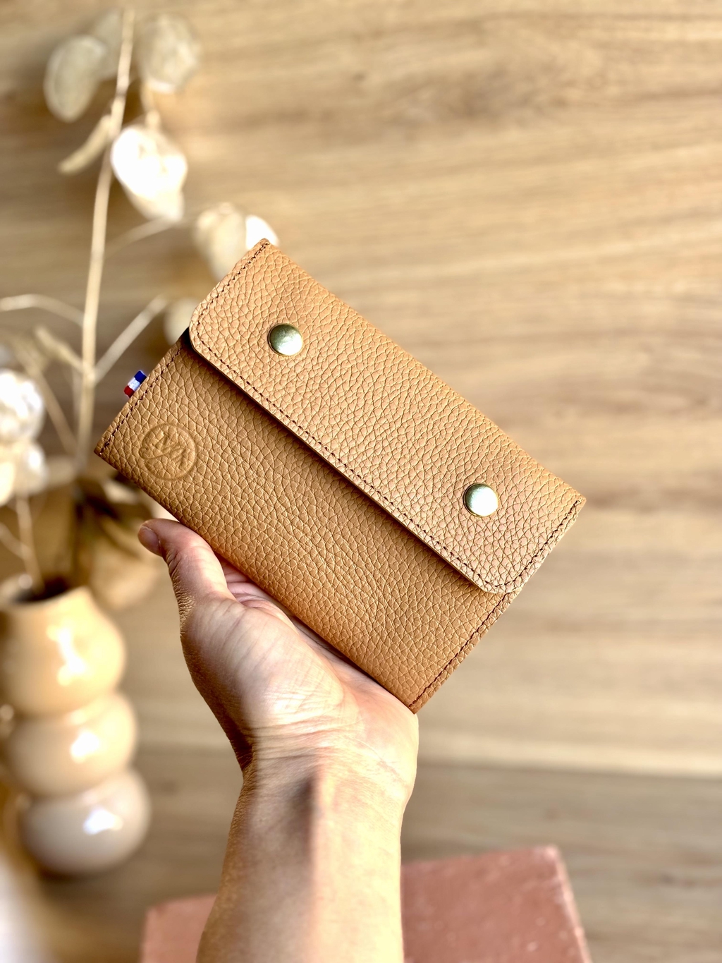 Un portefeuille pensé pour ceux qui aiment l’essentiel, sans compromis sur la qualité.

Fabriqué par mes soins, Marjorie Berthelomet, artisane maroquinière. Dans mon atelier à Ribérac, en Dordogne, France.

Matériaux & fabrication :

Cuir de vache grainé, italien certifié. Couleur marron.
Doublure cuir de porc pour une finition haut de gamme.
Ferme avec deux boutons pressions.
Logo estampé à chaud pour y déposer ma signature.
Étiquette ruban tricolore bleu, blanc, rouge – clin d'œil au savoir-faire français.
Fonctionnalités :
1 compartiment pièces de monnaie avec fermeture éclair.
1 compartiment papiers (carte grise, pièce d'identité...).
2 compartiments cartes pouvant contenir plusieurs cartes chacun.
Simple, fonctionnel, intemporel.
Dimensions : L 15 cm x H 10 cm x l 2 cm.
Délais d'expédition: 2 à 4 jours ouvrés. En France uniquement.

Livré avec un pochon tissu en coton recyclé, fait maison.