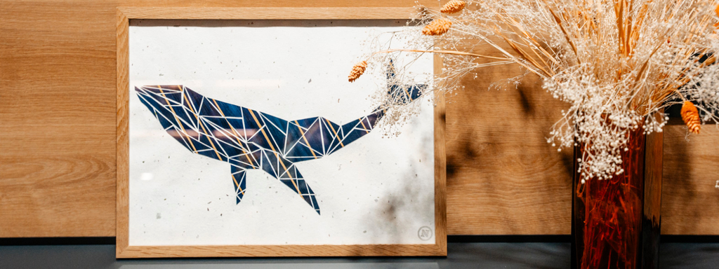 Atelier de marqueterie de paille près de Rennes, bannière avec un cadre en chêne massif et la marqueterie de paille d'une baleine bleu et jaune origamique sur un papier algue et mica