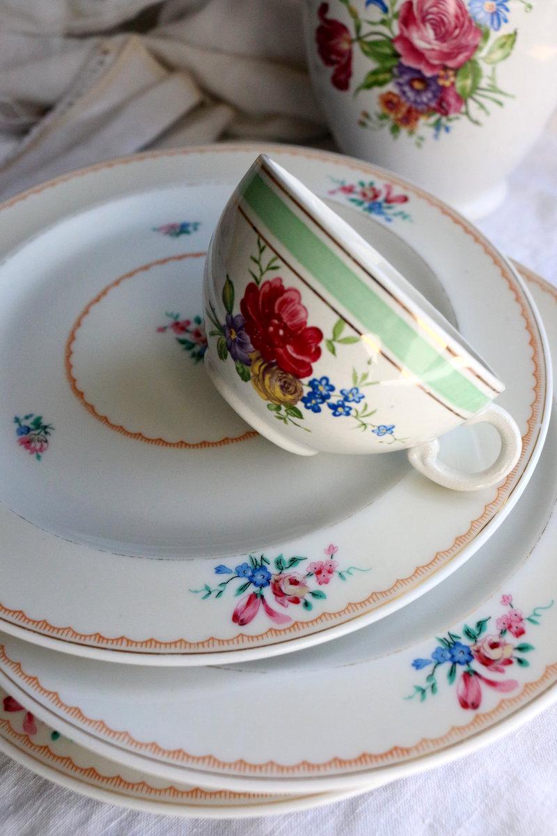 Tasse Lunéville décorée de motifs floraux couchée sur une assiette à dessert Vignaud assortie, présentée à côté du texte expliquant l’esprit Vaisselle Bavarde.