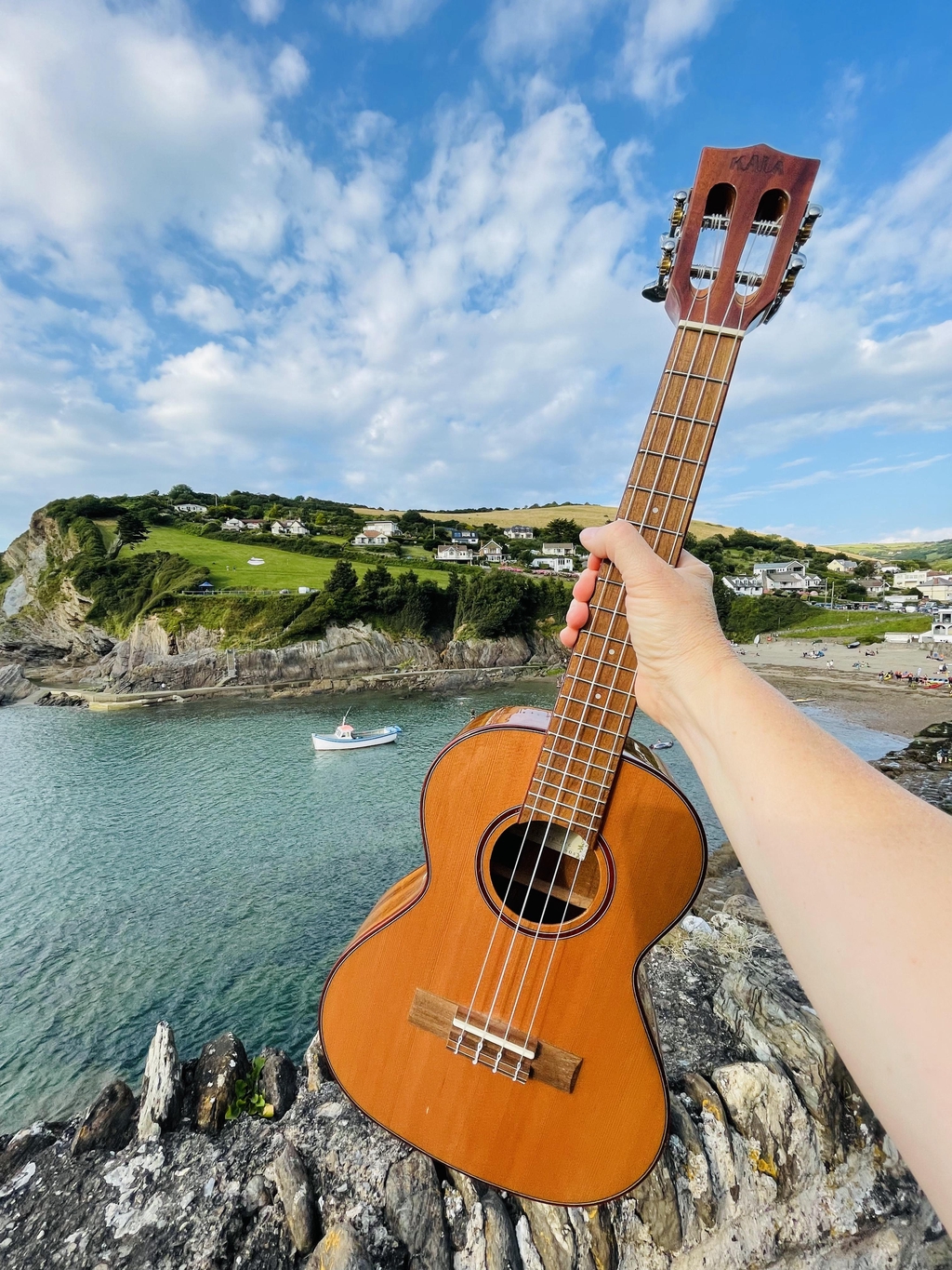 Holding a ukulele on Combe Martin Beach
