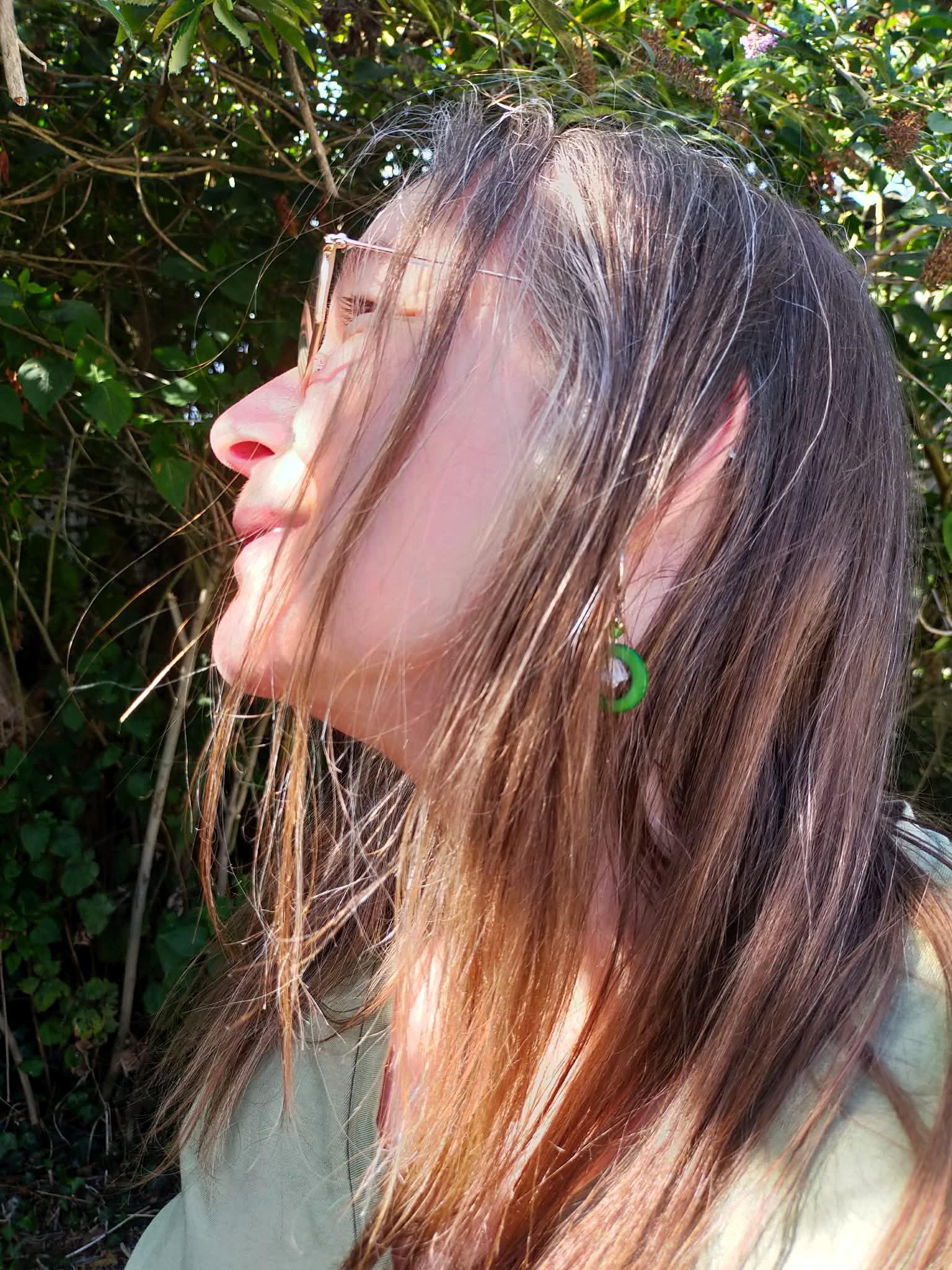 Portrait de profil de la créatrice de bijoux Izia Katell, portant une boucle d'oreille artisanale en acier inoxydable