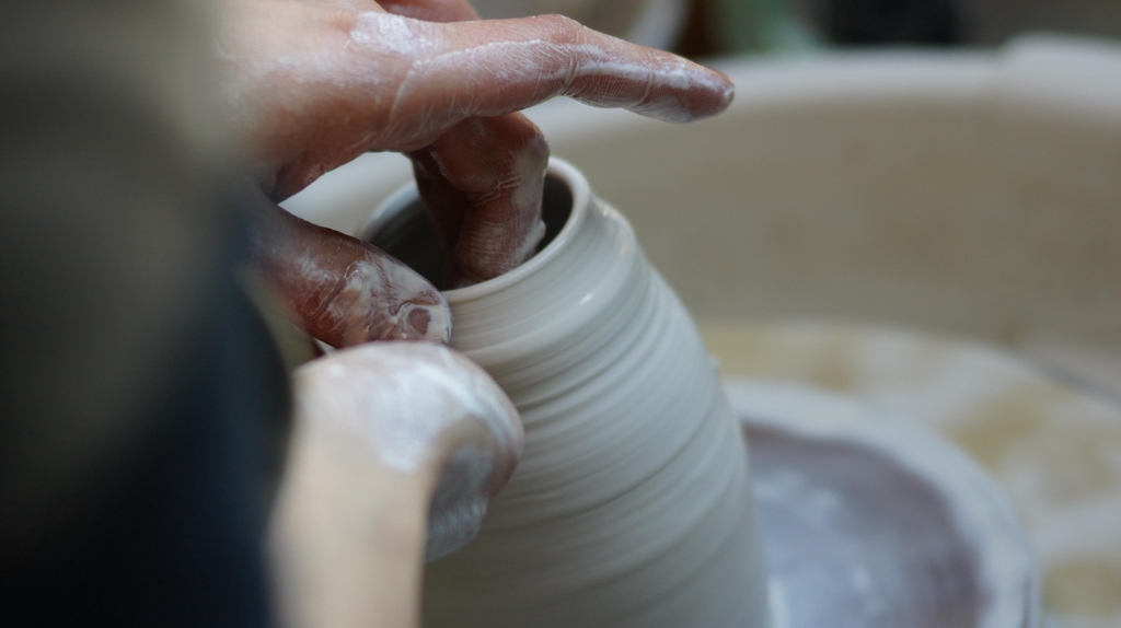 pièce en porcelaine en train d'être tourée sur un tour de potier