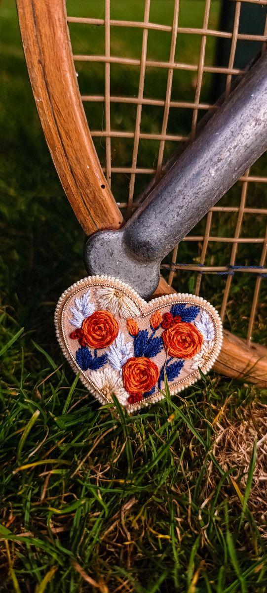 Broches brodées à la main en forme de cœur. Pièces limitées, finitions perles ou fil blanc, élégance artisanale en série limitée.