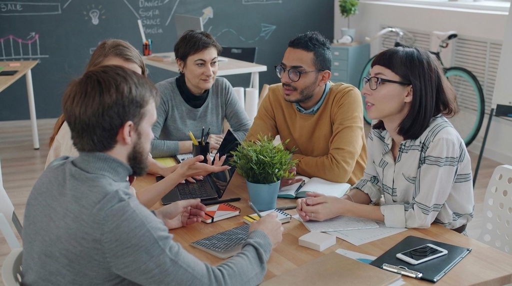 Group of people talking in a creative shared office during staff meeting
