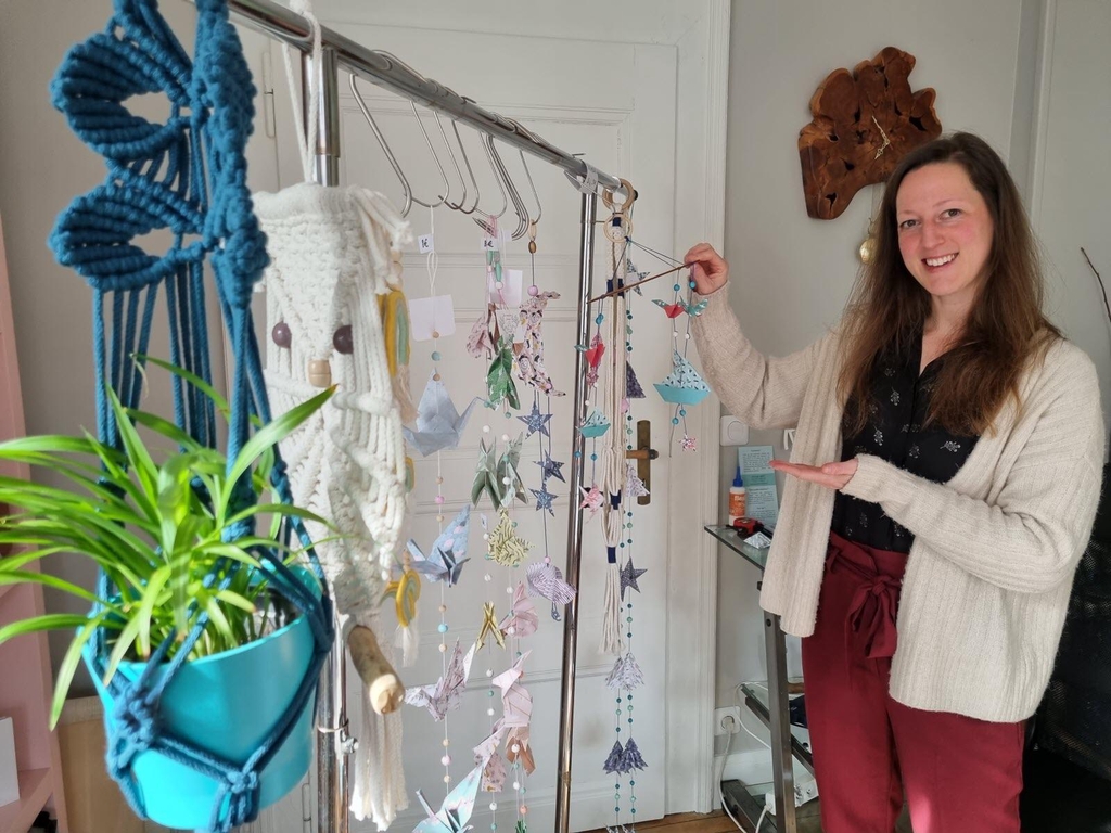 La créatrice, Jeanne, présente ses réalisations : des suspensions pour plante en macramé, des guirlandes en origami et un mobile bébé sur le thème de la mer. 