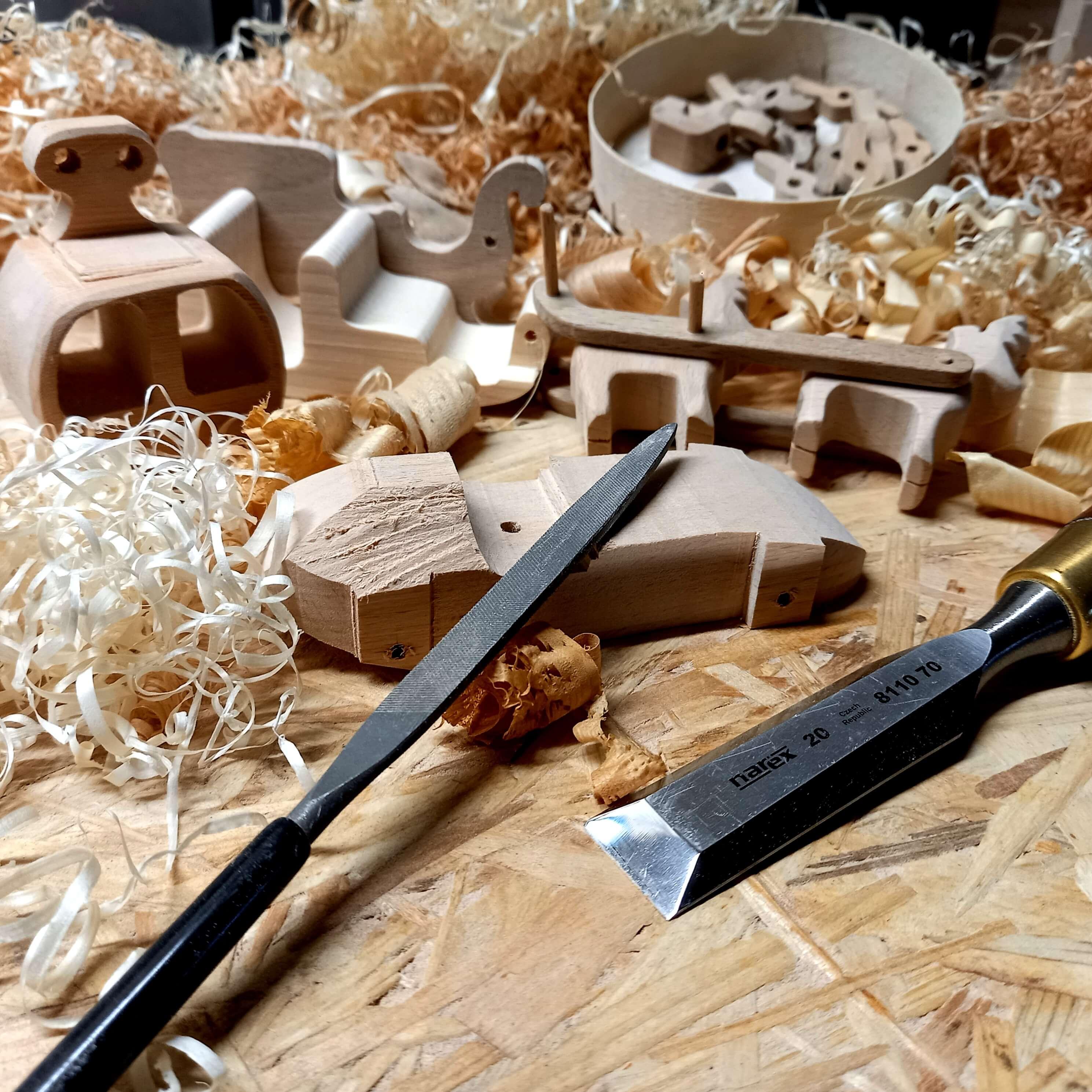 Petite voiture en bois incomplète en cours de poncage. Une scène d'atelier artisanal avec les outils à mains